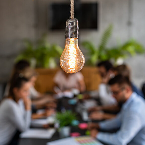Lightbulb with team of people working in background